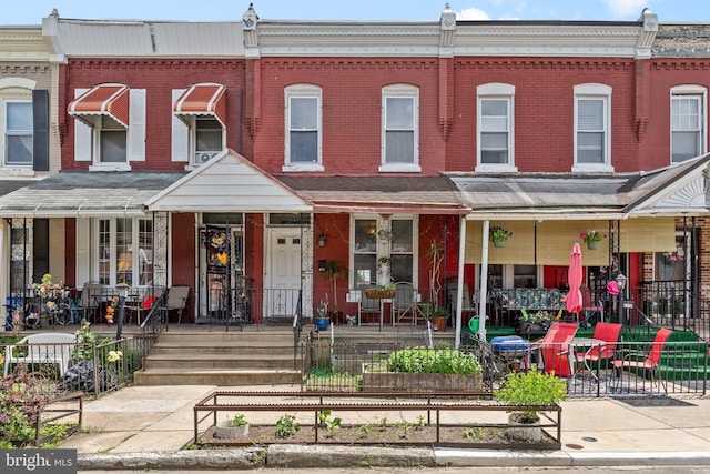 4734 Upland St, Philadelphia, PA 19143 - townhome / multi-family property featuring brick siding, a porch, and a vegetable garden