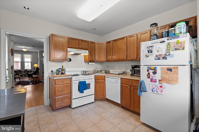 4734 Upland St, Philadelphia, PA 19143 - kitchen with white appliances, under cabinet range hood, light countertops, brown cabinets, and light tile patterned floors