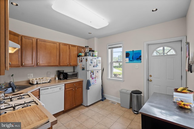 4734 Upland St, Philadelphia, PA 19143 - kitchen with white appliances, brown cabinets, light countertops, light tile patterned floors, and recessed lighting