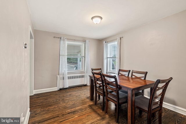 dining area featuring radiator heating unit, dark wood finished floors, and baseboards