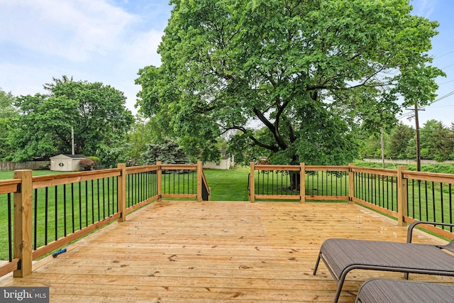 wooden terrace featuring a storage unit, an outbuilding, a yard, and view of scattered trees
