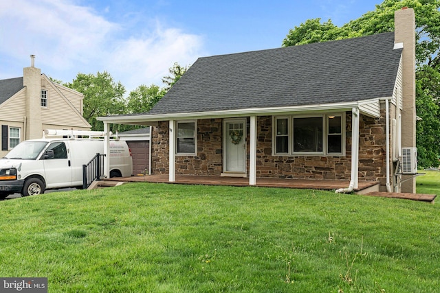view of front facade featuring stone siding, a chimney, a front yard, and roof with shingles