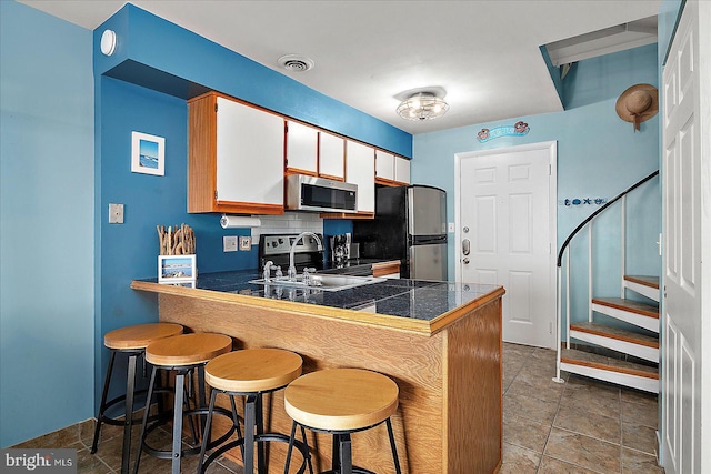 104 127th St Unit 326B, Ocean City, MD 21842 - kitchen with appliances with stainless steel finishes, a sink, a peninsula, tasteful backsplash, and a kitchen bar