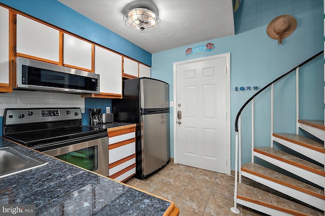 104 127th St Unit 326B, Ocean City, MD 21842 - kitchen featuring appliances with stainless steel finishes, white cabinets, dark countertops, backsplash, and a sink