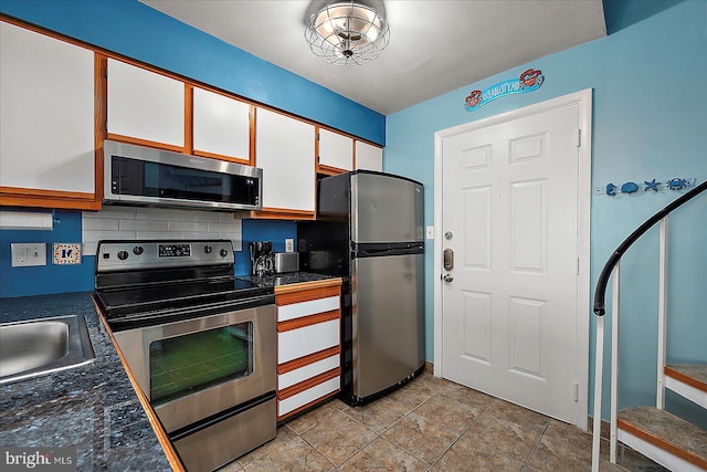 104 127th St Unit 326B, Ocean City, MD 21842 - kitchen featuring appliances with stainless steel finishes, dark countertops, white cabinets, a sink, and tasteful backsplash