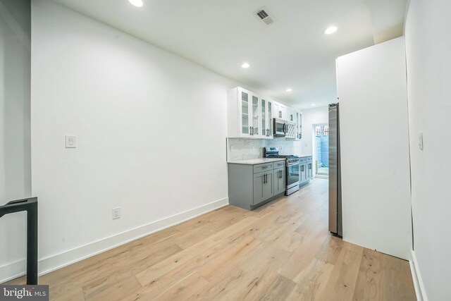 1309 S 32nd St, Philadelphia, PA 19146 - kitchen featuring stainless steel appliances, recessed lighting, light wood-type flooring, glass insert cabinets, and tasteful backsplash