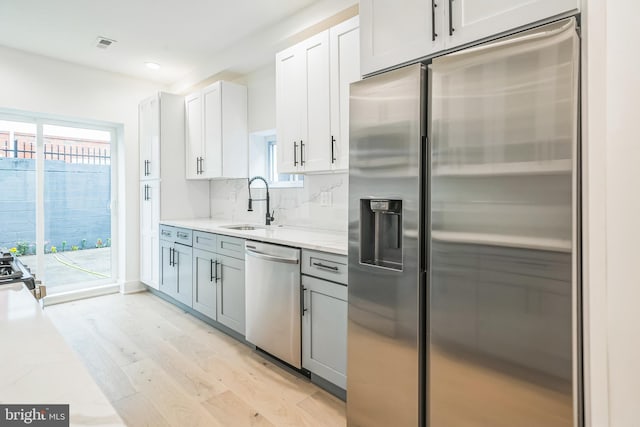 1309 S 32nd St, Philadelphia, PA 19146 - kitchen with appliances with stainless steel finishes, a sink, light wood-style flooring, light stone counters, and backsplash