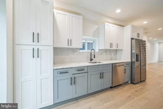 1309 S 32nd St, Philadelphia, PA 19146 - kitchen with appliances with stainless steel finishes, a sink, backsplash, light wood finished floors, and white cabinetry