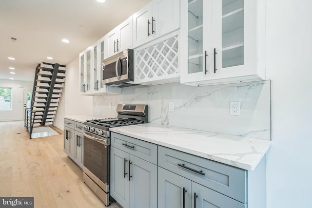 1309 S 32nd St, Philadelphia, PA 19146 - kitchen with appliances with stainless steel finishes, light wood-style floors, decorative backsplash, white cabinetry, and light stone countertops