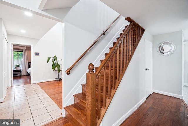 stairway with baseboards, wood finished floors, and recessed lighting