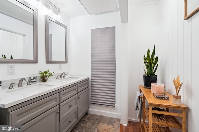 bathroom with double vanity, baseboards, and stone finish flooring