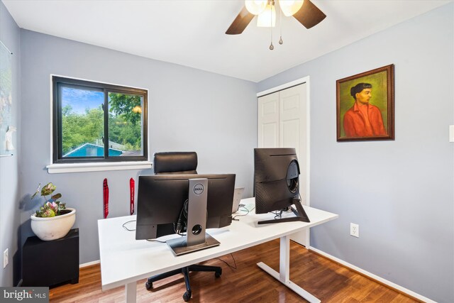 office area with a ceiling fan, wood finished floors, and baseboards