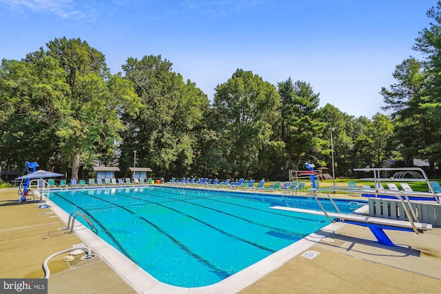community pool featuring view of wooded area