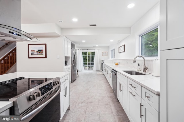 kitchen with appliances with stainless steel finishes, a sink, ventilation hood, white cabinetry, and recessed lighting