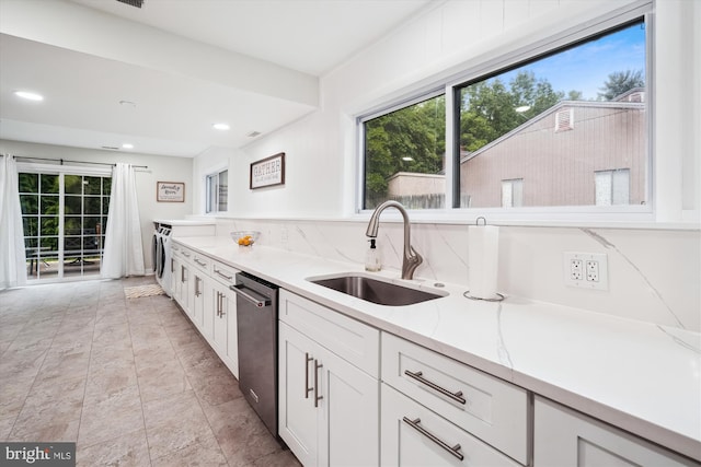 kitchen with a sink, washing machine and clothes dryer, stainless steel dishwasher, plenty of natural light, and recessed lighting