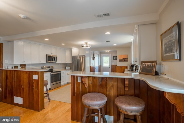 3706 Bestpitch Ferry Rd, Cambridge, MD 21613 - kitchen with appliances with stainless steel finishes, a peninsula, white cabinetry, light wood finished floors, and light countertops