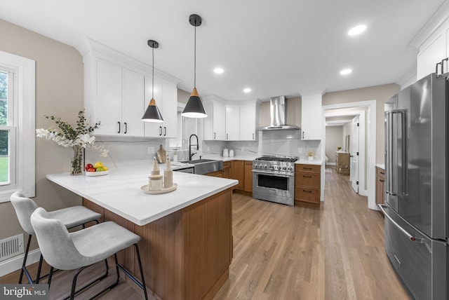 20 Hathaway Dr, Princeton Junction, NJ 08550 - kitchen featuring high end appliances, wall chimney exhaust hood, a sink, a peninsula, and light wood-type flooring