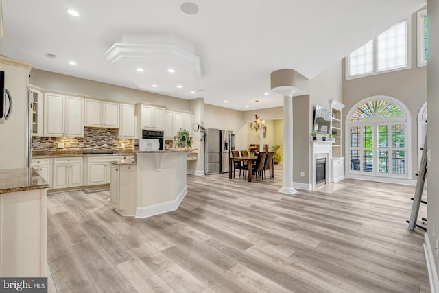 12723 Lady Somerset Ln, Fairfax, VA 22033 - kitchen with black oven, light stone counters, a kitchen island, stainless steel refrigerator with ice dispenser, and light wood-style flooring