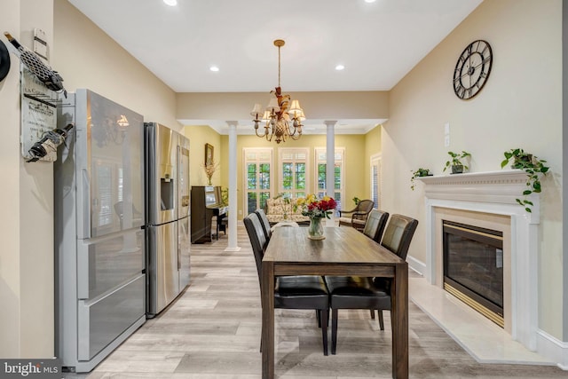 12723 Lady Somerset Ln, Fairfax, VA 22033 - dining space featuring light wood-style floors, recessed lighting, decorative columns, a chandelier, and a fireplace