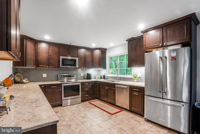 9213 Fairlane Pl, Laurel, MD 20708 - kitchen featuring stainless steel appliances, a sink, dark brown cabinets, tasteful backsplash, and light tile patterned floors