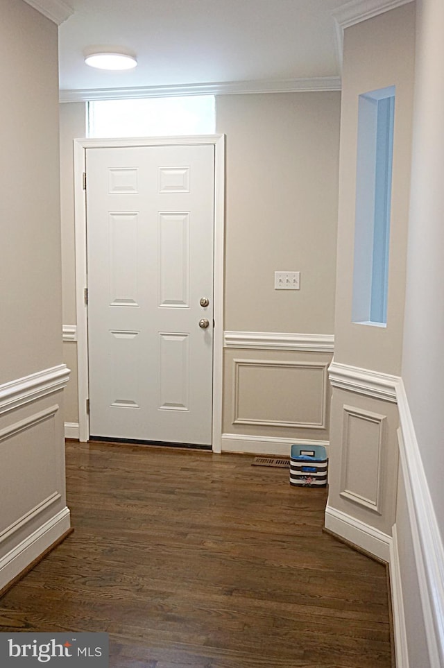 foyer entrance featuring ornamental molding, dark wood-type flooring, a wainscoted wall, and a decorative wall