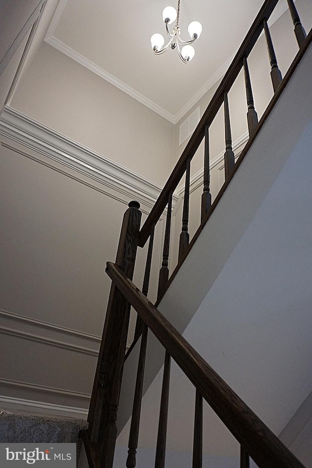staircase with a chandelier and ornamental molding
