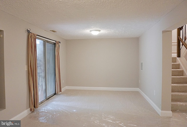 unfurnished room with stairway, baseboards, and a textured ceiling
