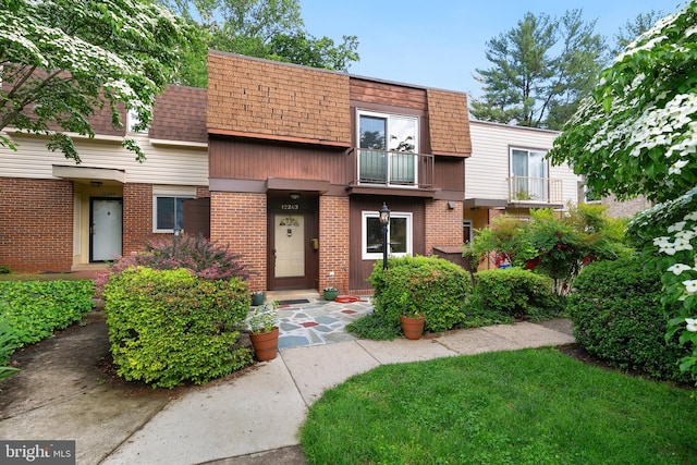 townhome / multi-family property featuring mansard roof, brick siding, and a shingled roof