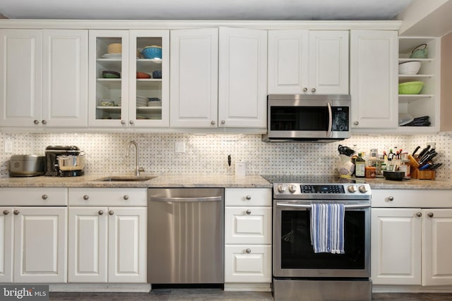 kitchen with appliances with stainless steel finishes, a sink, and white cabinetry