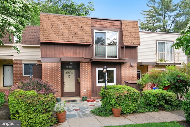 multi unit property with brick siding, mansard roof, and a balcony