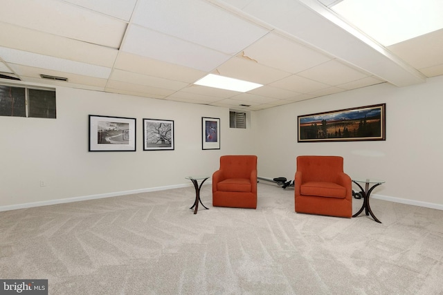 living area with carpet, a drop ceiling, and baseboards