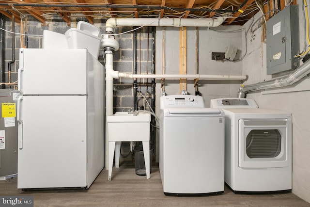 clothes washing area featuring electric panel, washer and clothes dryer, electric water heater, and wood finished floors