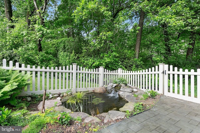 view of patio with fence and a garden pond