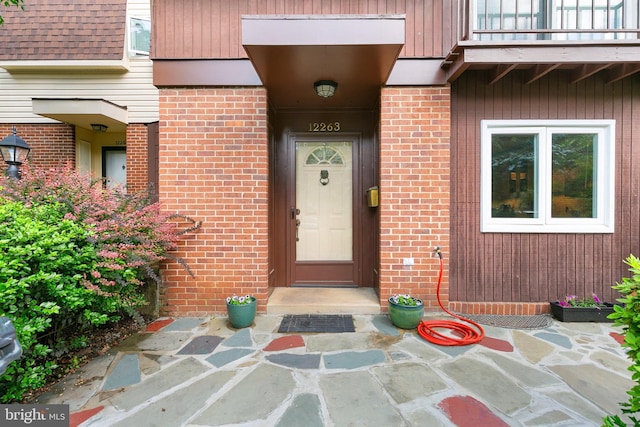 property entrance with brick siding and a balcony
