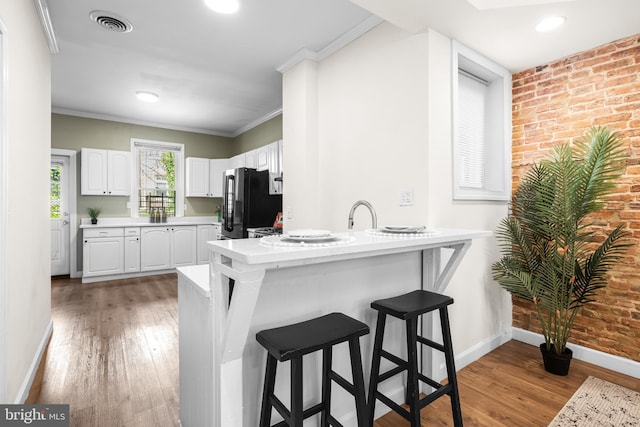 326 E 28th St, Baltimore, MD 21218 - kitchen with baseboards, freestanding refrigerator, a peninsula, light wood-style flooring, and a breakfast bar area