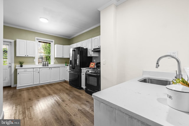 326 E 28th St, Baltimore, MD 21218 - kitchen featuring range with gas stovetop, a sink, light wood-style floors, black fridge with ice dispenser, and white cabinets