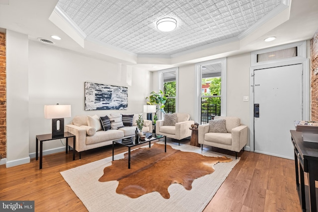 326 E 28th St, Baltimore, MD 21218 - living room with crown molding, a raised ceiling, light wood-style floors, baseboards, and an ornate ceiling