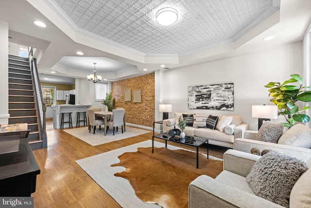 326 E 28th St, Baltimore, MD 21218 - living room with a tray ceiling, crown molding, a chandelier, stairway, and light wood-type flooring