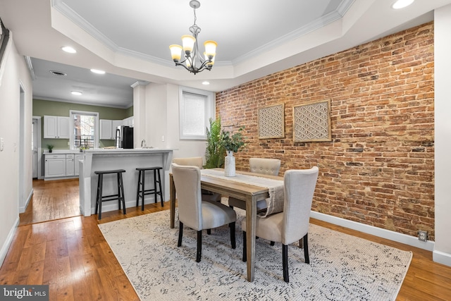 326 E 28th St, Baltimore, MD 21218 - dining room featuring a chandelier, ornamental molding, light wood-style flooring, baseboards, and brick wall