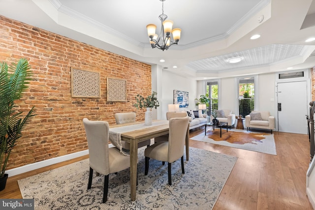 326 E 28th St, Baltimore, MD 21218 - dining area with a tray ceiling, a chandelier, crown molding, wood finished floors, and brick wall