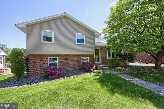tri-level home featuring brick siding and a front yard