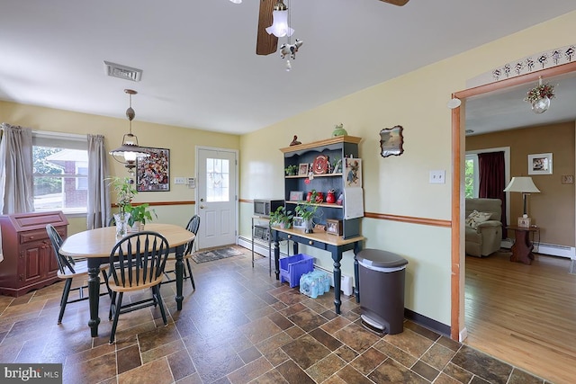 dining area with healthy amount of natural light, dark stone finish flooring, and baseboards