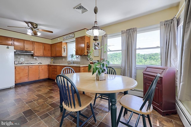 dining area with baseboard heating, stone tile floors, and a ceiling fan