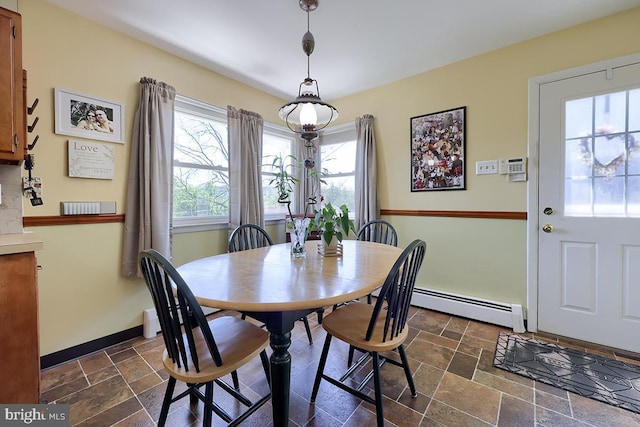 dining area with a baseboard heating unit, stone tile flooring, and baseboards