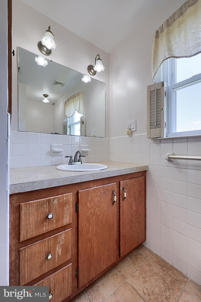 bathroom with tile walls, vanity, tile patterned floors, and healthy amount of natural light