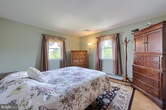 bedroom with baseboard heating and light wood-type flooring