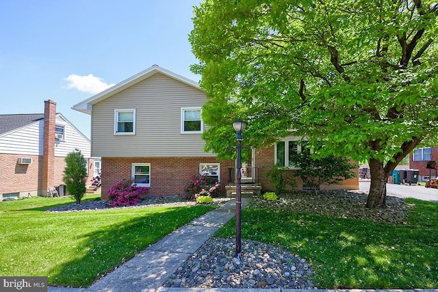 tri-level home with a front lawn and brick siding