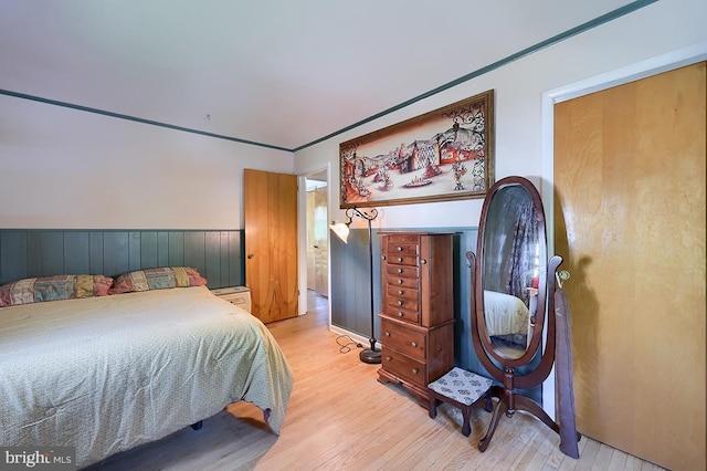 bedroom with light wood-style floors and wainscoting