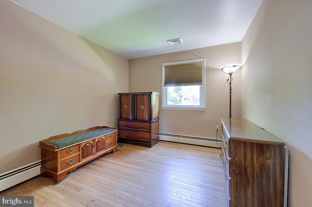 bedroom with a baseboard heating unit and light wood finished floors