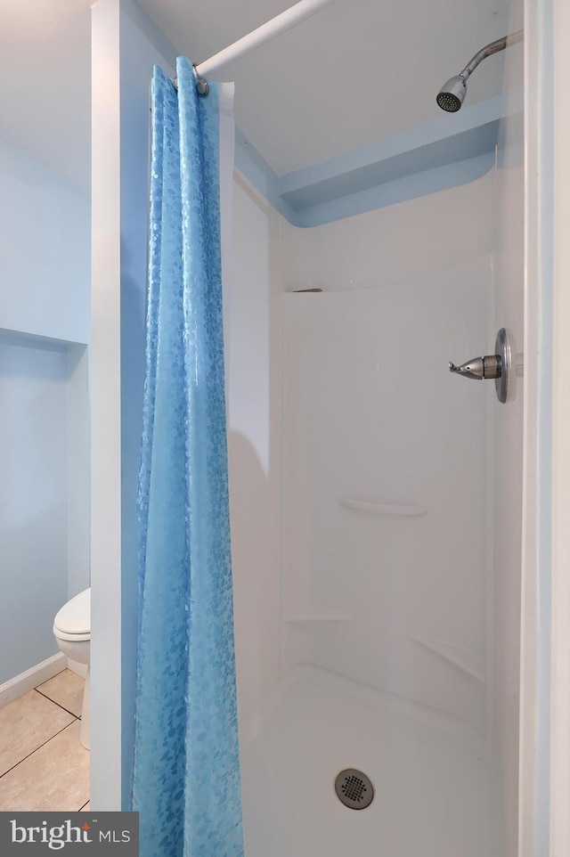 bathroom featuring a stall shower, tile patterned flooring, and toilet